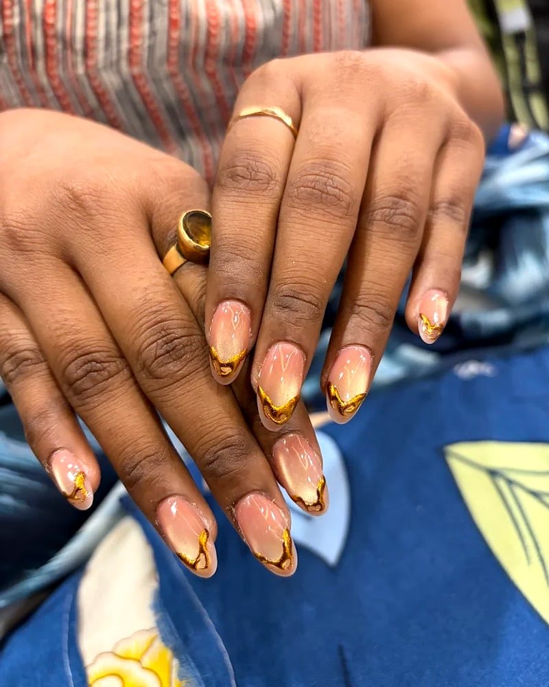 Gold-foil French tip nail extensions on almond nails at Nail O Lash